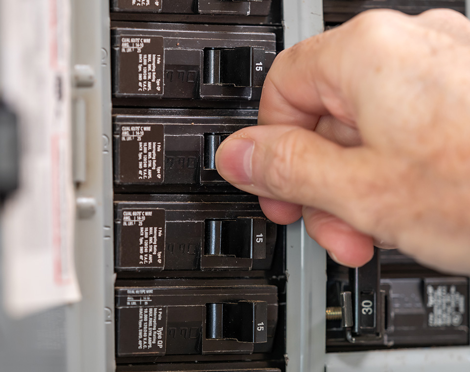 a hand touching the electrical panel circuit breaker